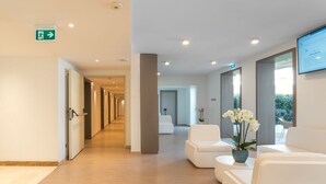 A modern reception area with a wooden floor, white seating, and a digital display. - Stele di Nora (Pula)