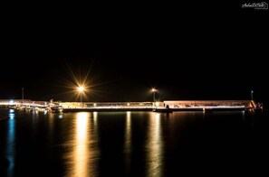 A waterfront hotel with a long, illuminated structure and boats docked at the pier. - Quasi in Porto Rooms (Castellabate)