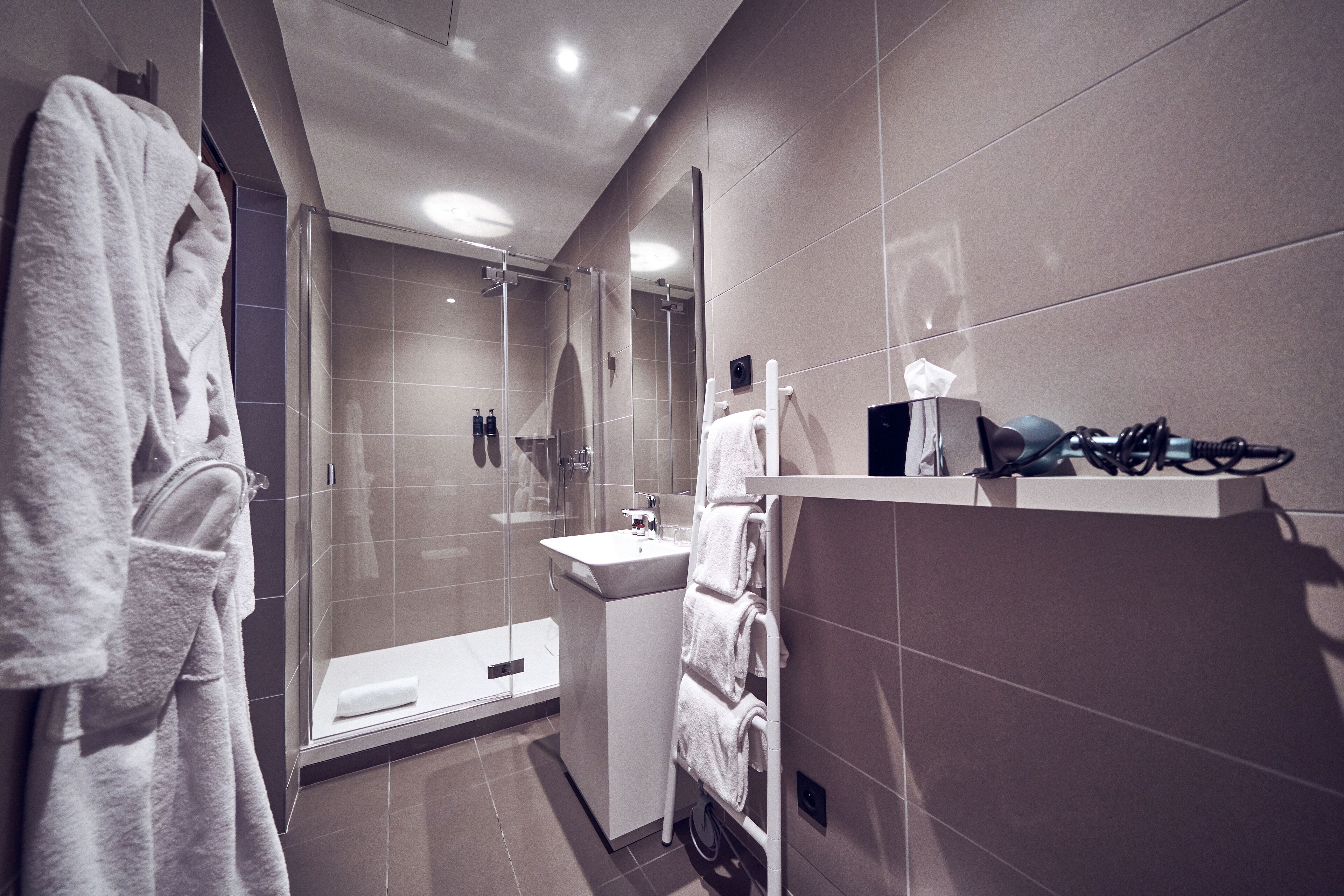 Un baño moderno con cabina de ducha de vidrio, lavamanos y un perchero para toallas.