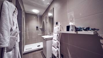 Un baño moderno con cabina de ducha de vidrio, lavamanos y un perchero para toallas.