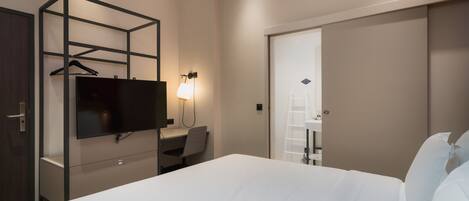 Una habitación de hotel con cama, escritorio, televisión y armario.