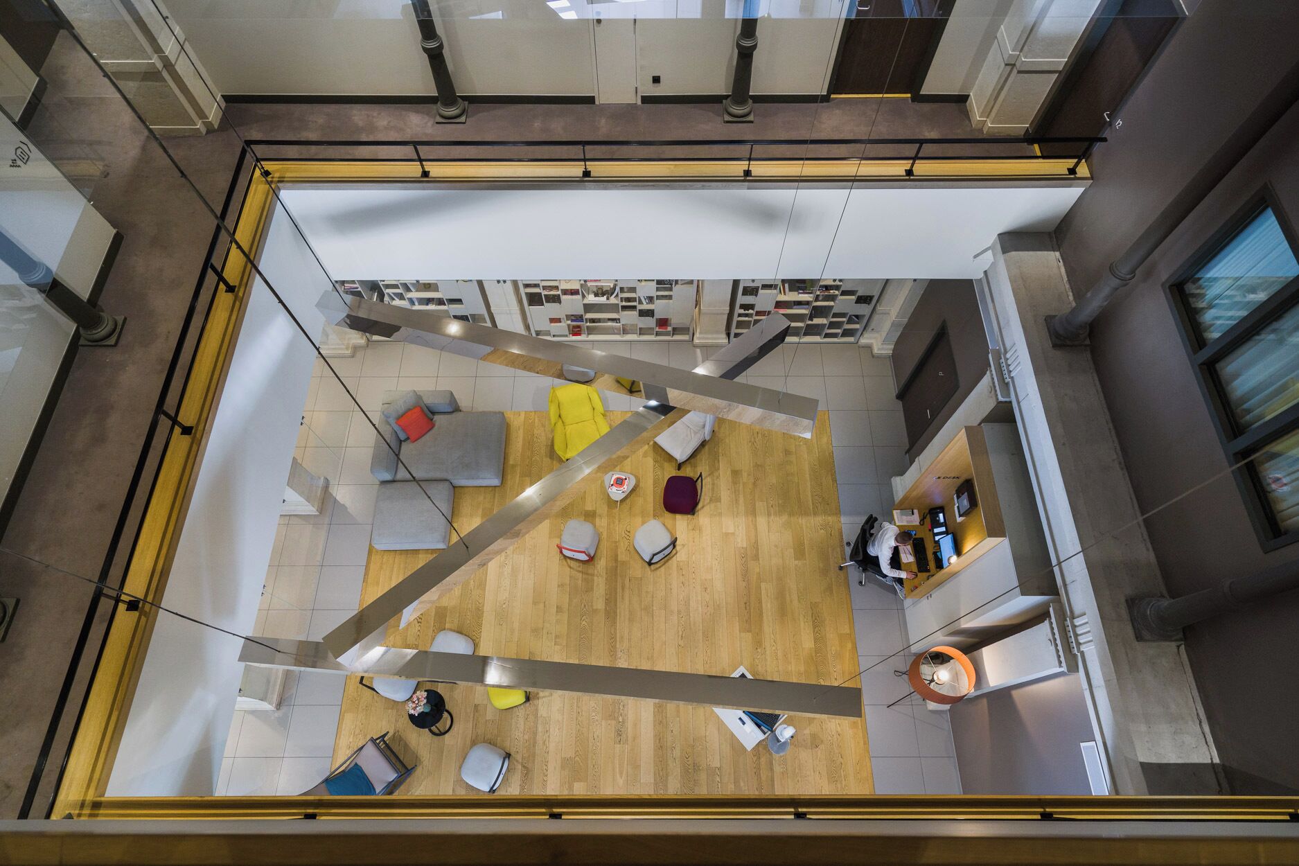 A modern interior with a wooden floor, seating areas, and a reception desk.