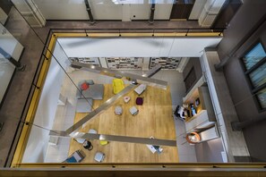 A modern interior with a wooden floor, seating areas, and a reception desk.