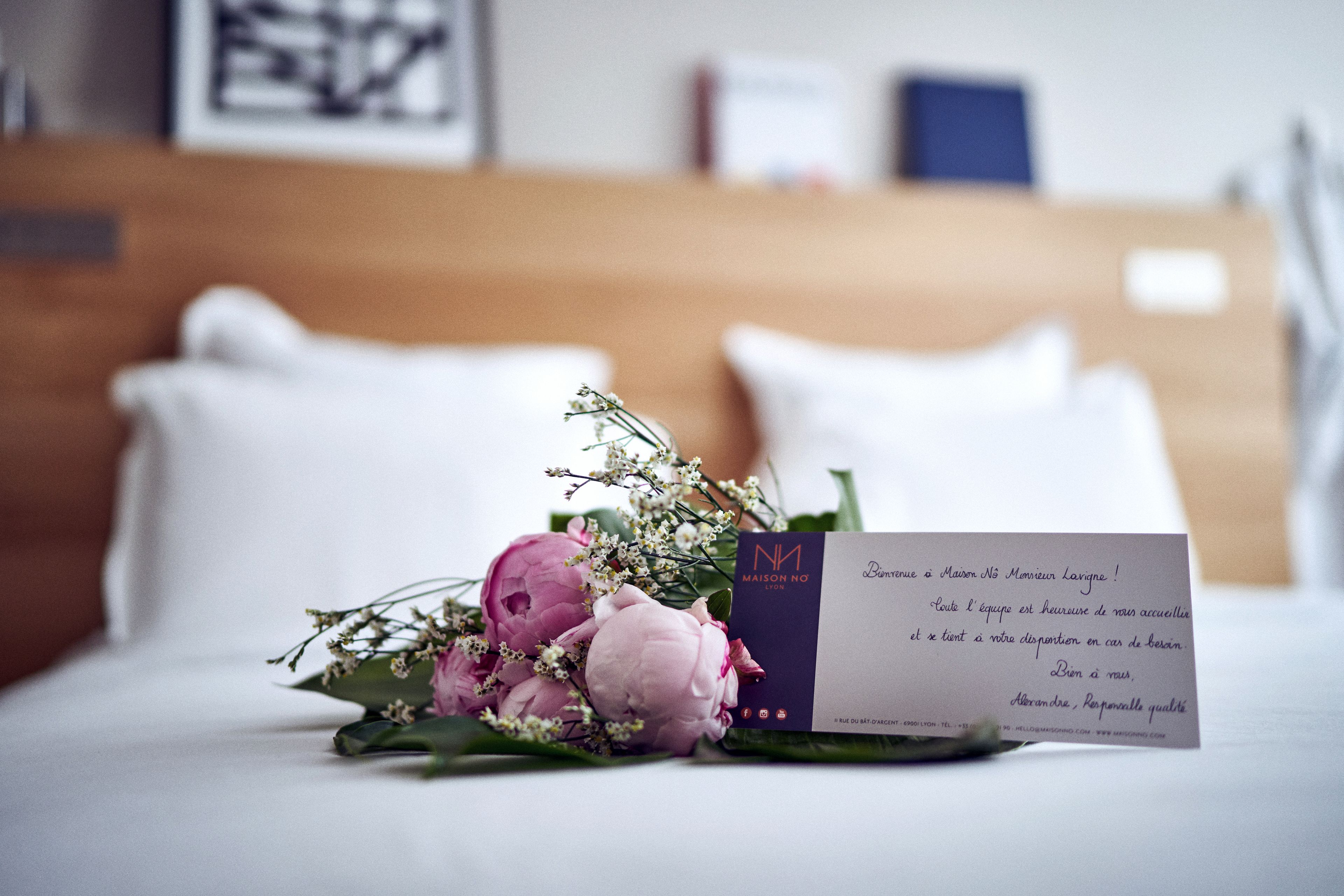 A bed with a bouquet of flowers and a business card on it.