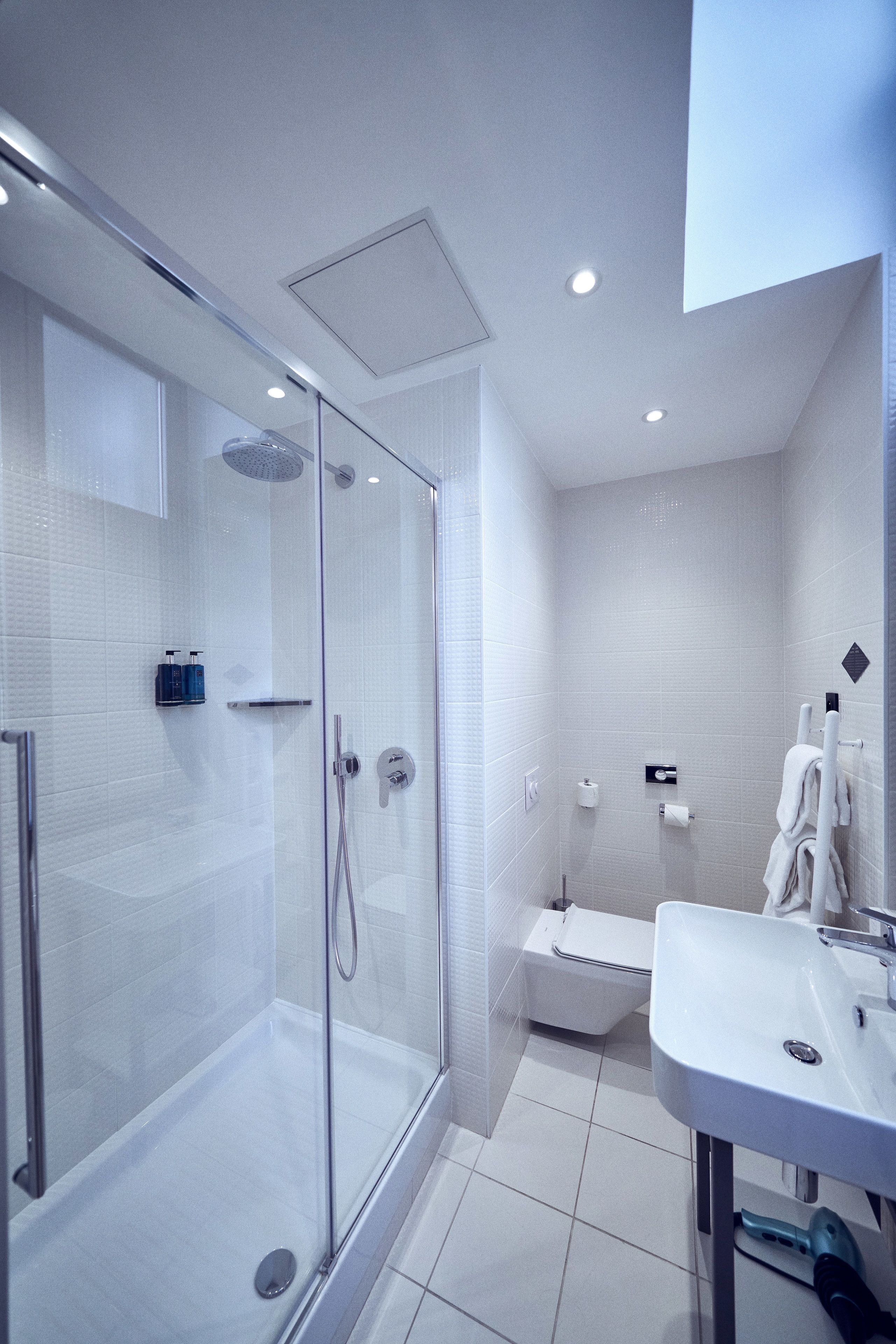 A modern bathroom with a glass-enclosed shower, a white sink, and a toilet.