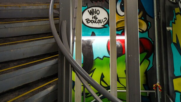 A staircase with graffiti art and a sign that reads "WHO IS YOU?" - Maison Nô (Lyon)