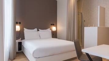 A modern hotel room with a large bed, bedside lamps, a desk, and a chair.