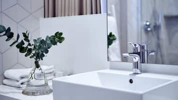 A modern bathroom with a white sink, a mirror, and a plant.