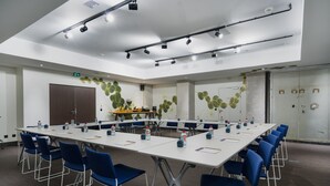 A conference room with a long table, blue chairs, and water bottles. - Maison Nô (Lyon)