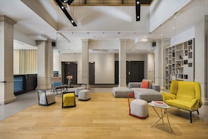 A spacious lobby with a wooden floor, modern furniture, and a large bookshelf. - Maison Nô (Lyon)