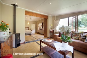 Un amplio espacio de estar con chimenea, un sofá, una mesa de centro y vistas al exterior.