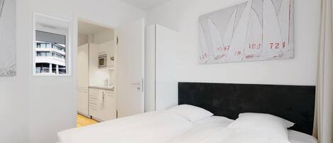 Un dormitorio con una cama, cabecera oscura y una obra de arte abstracta colgada en la pared.