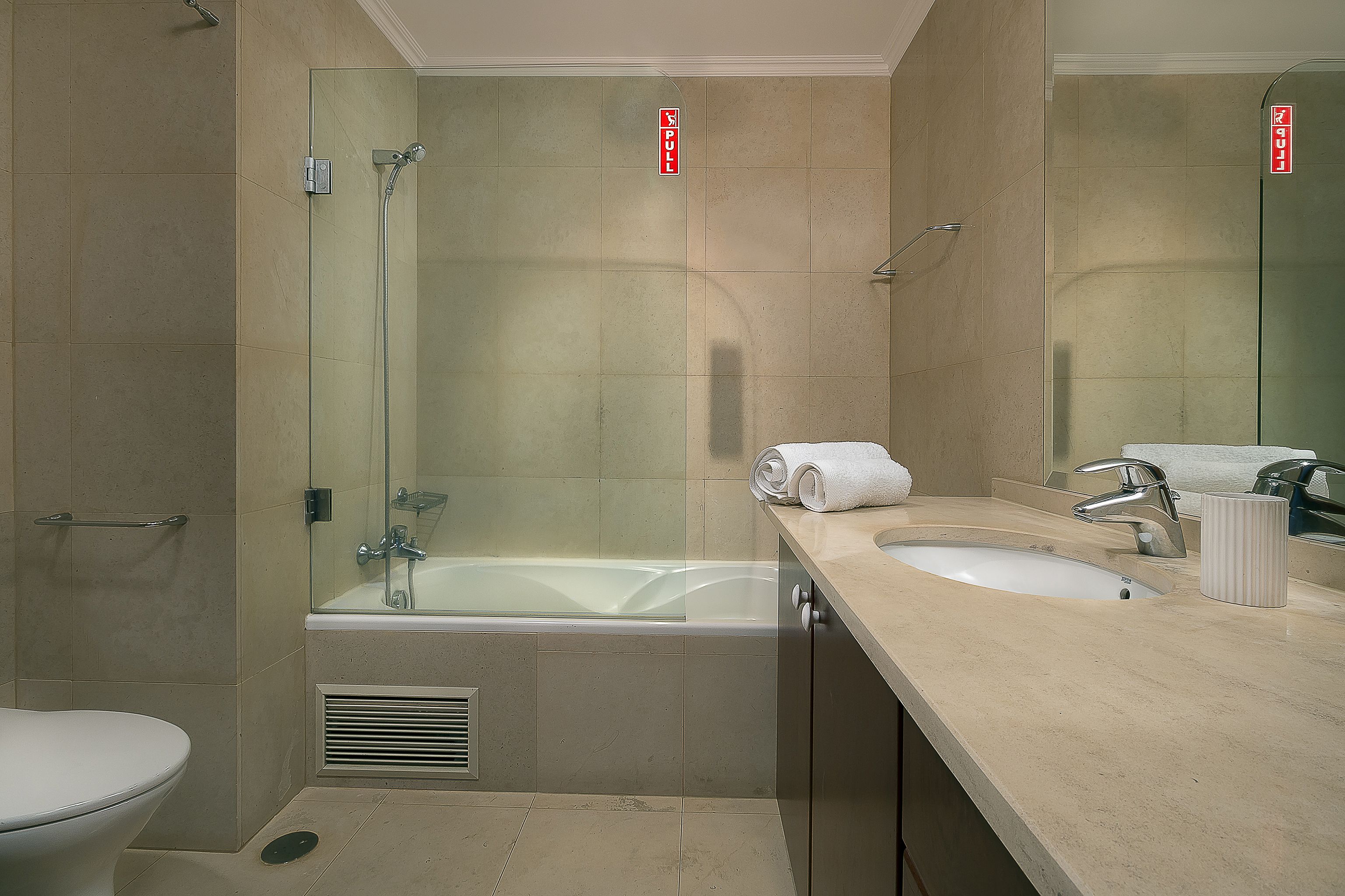 A modern bathroom with a glass-enclosed shower, a bathtub, a sink with a mirror, and a toilet.