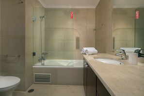 Ein modernes Badezimmer mit einer gläsernen Duschkabine, einer Badewanne, einem Waschbecken mit Spiegel und einer Toilette.