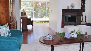 Un salón amplio con un gran ventanal, una chimenea y un sofá.