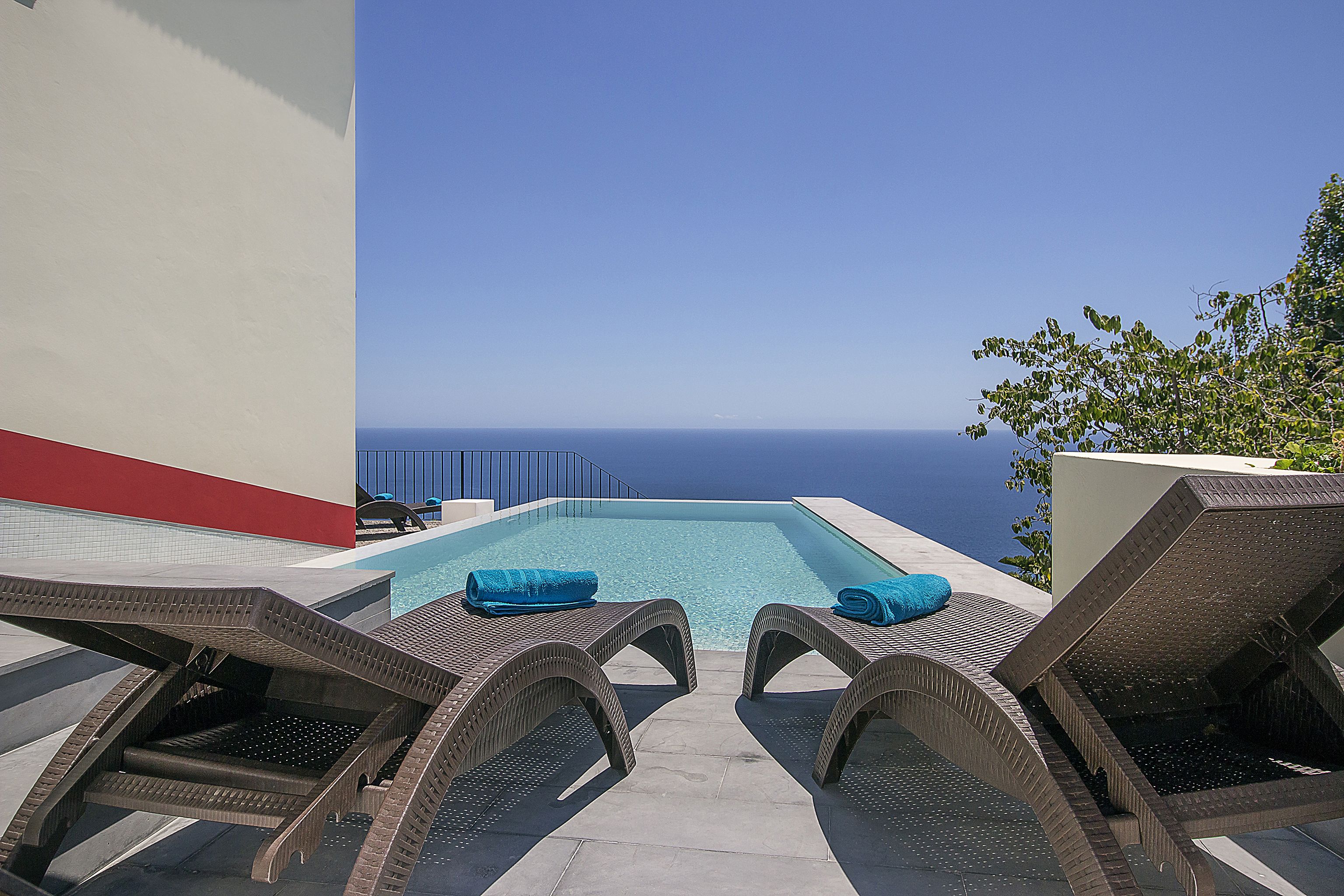 A poolside area with lounge chairs and a view of the ocean.
