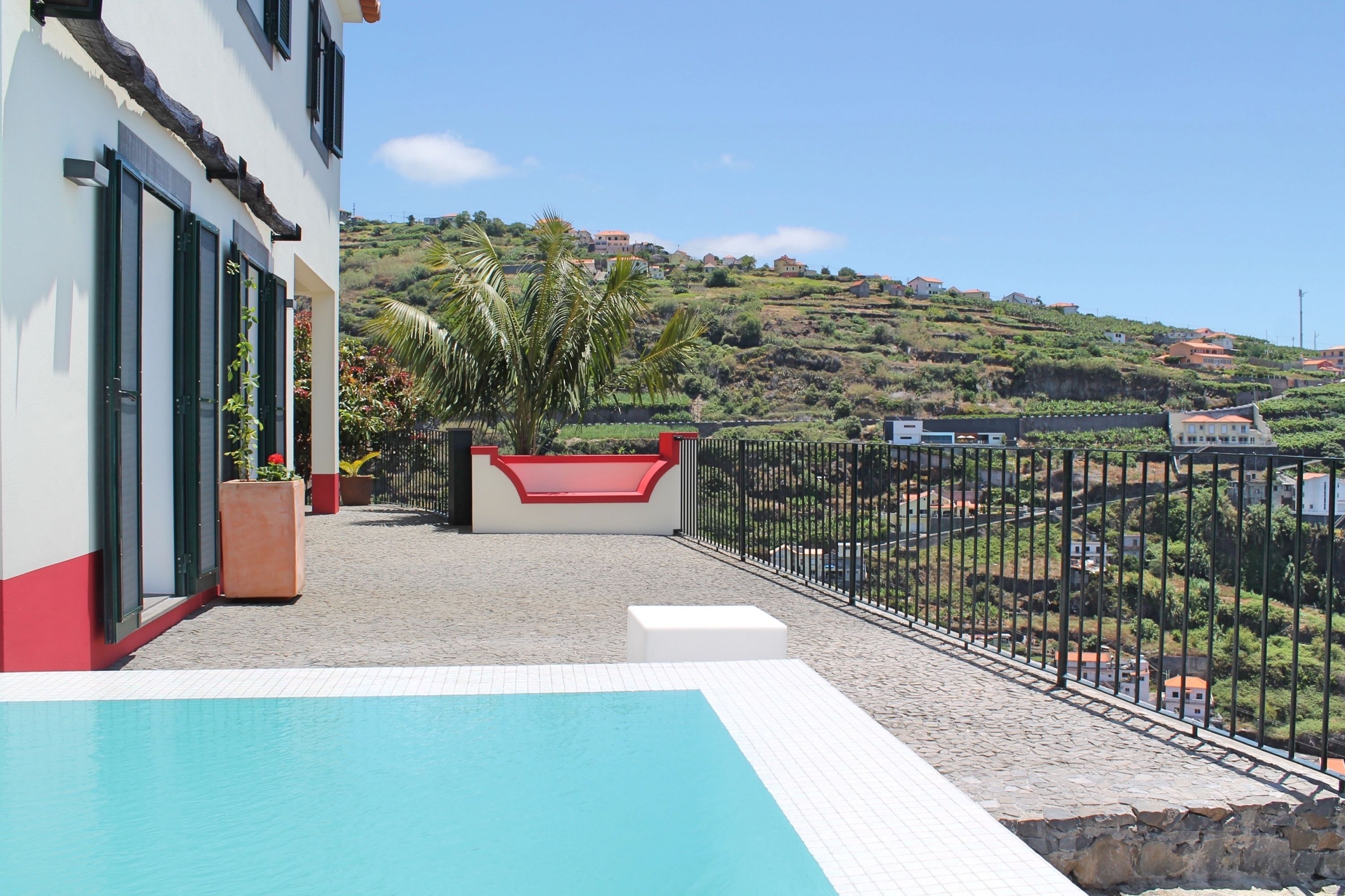 A pool area with a view of a hillside and houses.