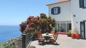 Un patio con una mesa redonda y sillas, con vistas al mar.