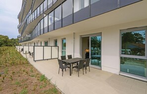 Ein modernes Gebäude mit einer Terrassenfläche, ausgestattet mit Tisch und Stühlen, großen Fenstern und Blick auf die umliegende Landschaft.