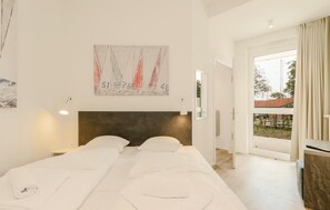 Ein Hotelzimmer mit einem großen Bett, einem Kopfteil, einem Gemälde, einem Fenster und Blick nach draußen.