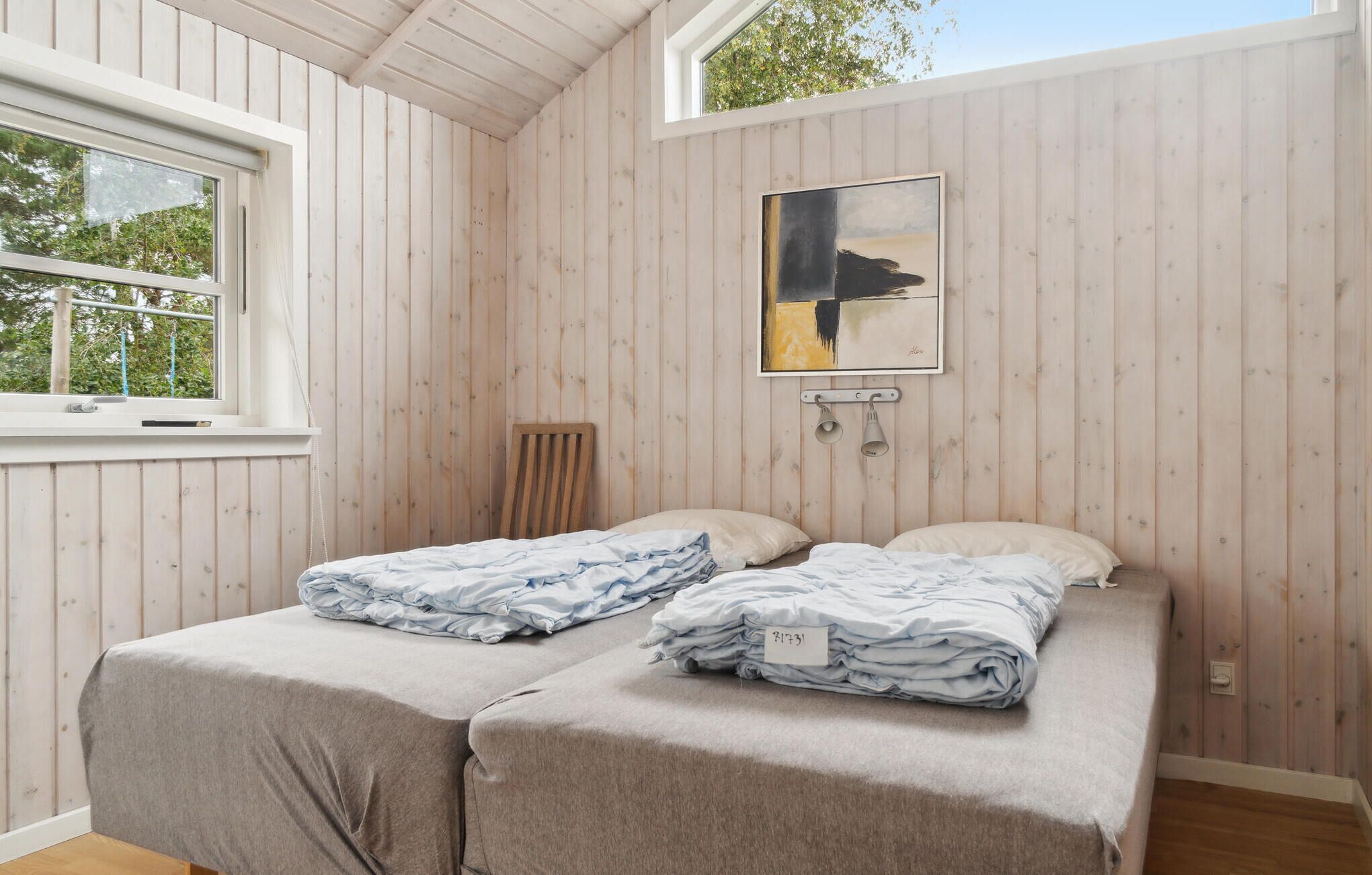 Una habitación con dos camas, un ventanal y un cuadro en la pared.