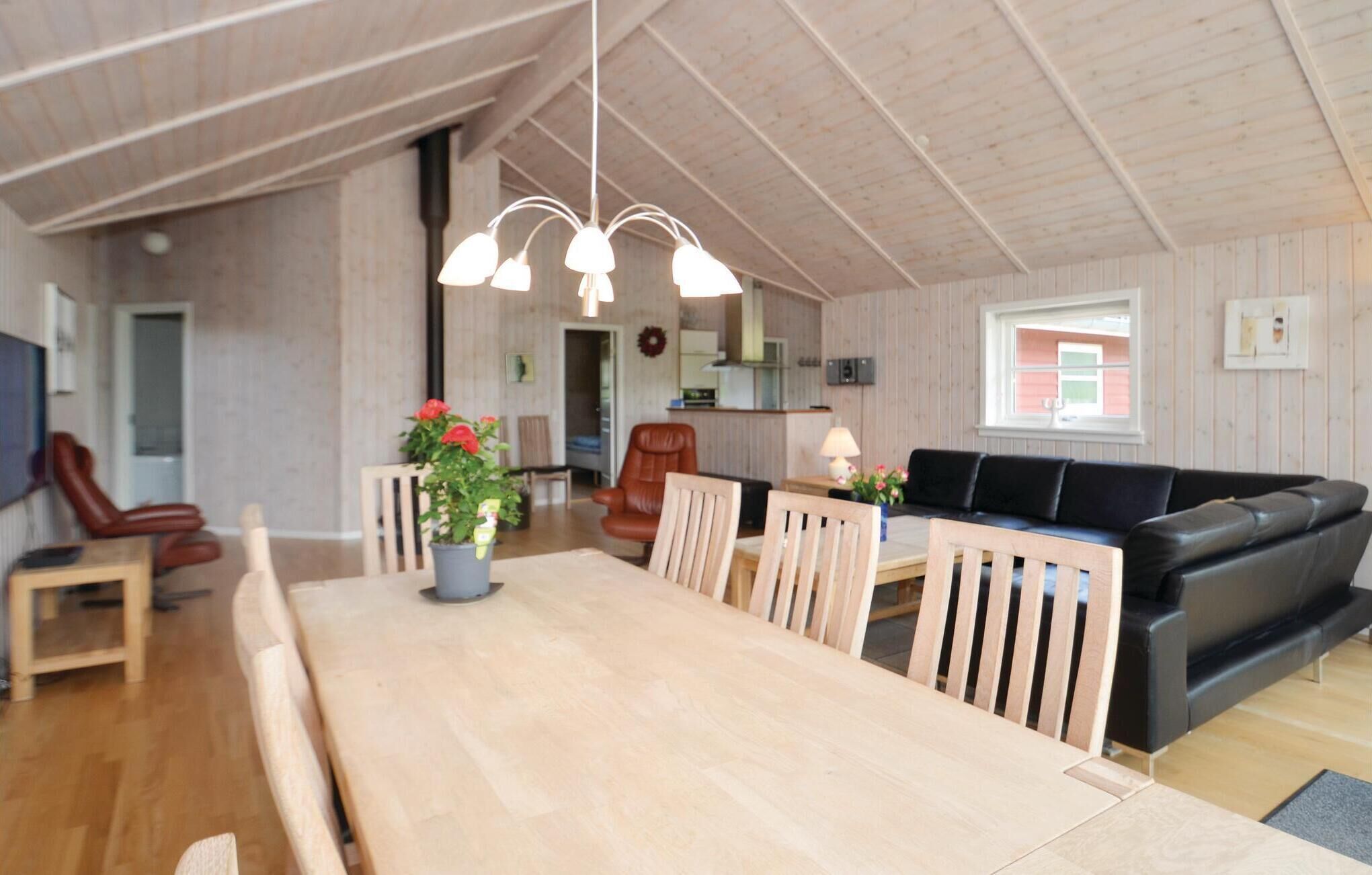 A spacious living area with a wooden dining table, a black sofa, and a wooden chair.