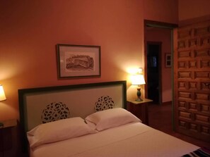 A hotel room with a bed, two lamps, a framed picture on the wall, and a patterned door. - Finca Santa Eufemia (Olmos de Ojeda)