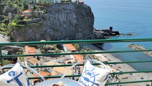 A balcony with a view of a coastal town, a rocky cliff, and a beach. - Casa Jardim Mar by Our Madeira (Calheta)