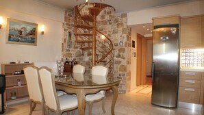 A dining area with a glass table and chairs, a spiral staircase, a stone wall, and a stainless steel refrigerator. - Awesome home in Artemida with WiFi (Artemida)