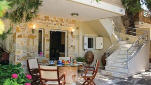 An outdoor dining area with stone walls, a table with chairs, a staircase, and a potted plant. - Awesome home in Artemida with WiFi (Artemida)