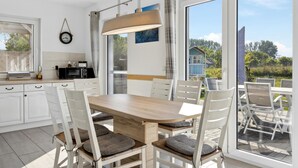 A modern kitchen with white cabinets, a wooden dining table, and chairs with woven cushions. - Nice home in Glowe with WiFi (Glowe)