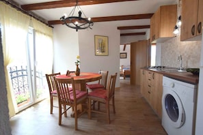 Una cocina con armarios de madera, una lavadora y un comedor con mesa y sillas.