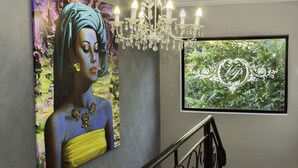 Interior moderno com uma pintura grande de uma mulher, um candelabro e um quadro emoldurado na parede.