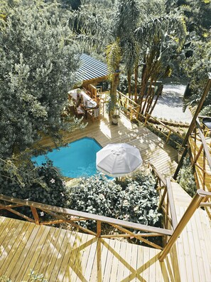 A wooden deck with a pool, surrounded by dense vegetation and a small structure with a sloped roof. - Forest Nature Spa (Plettenberg Bay)