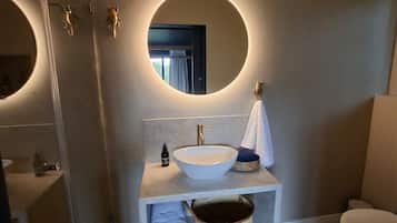 A modern bathroom with a round mirror, a vessel sink, and a toilet.
