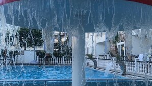A water feature with a red and blue structure, a pool, and a white railing. - Jasmin Blue Otel (Silifke)