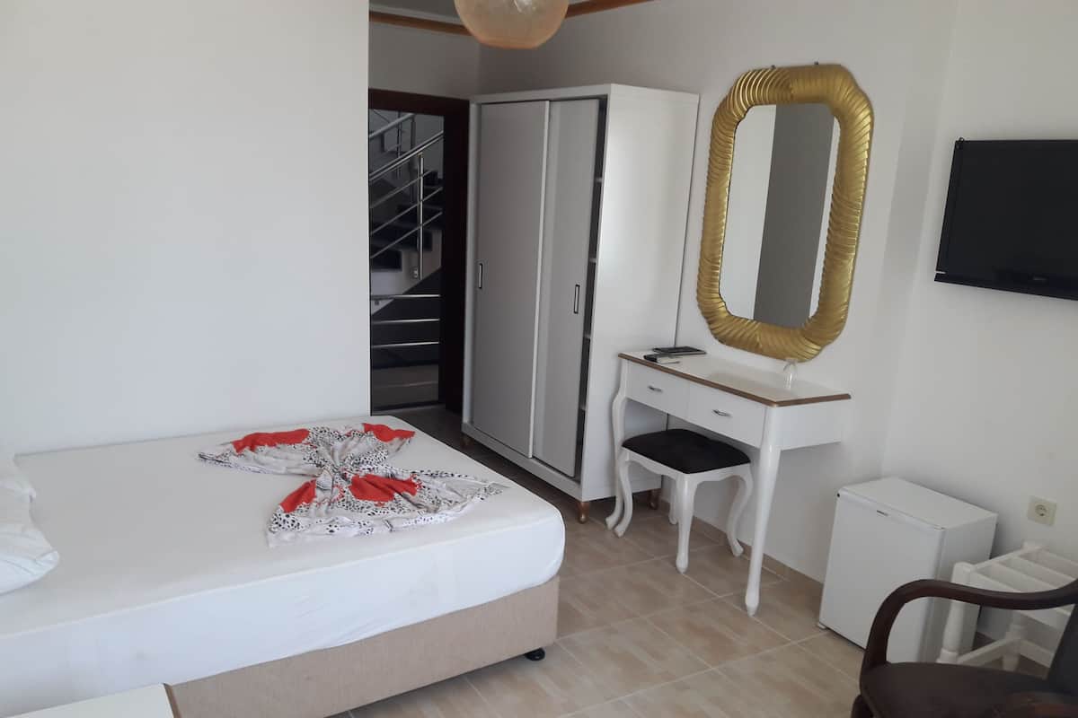 Un dormitorio con cama, tocador con espejo, silla, escritorio y armario.