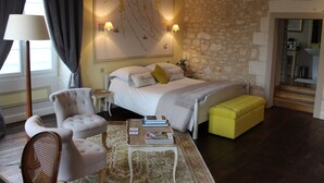 Une chambre à coucher comprenant un lit, une table de chevet, une chaise, un banc et une œuvre d’art accrochée au mur.