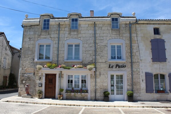 Un bâtiment en pierre avec une enseigne indiquant « Le Patio » et une porte en bois.