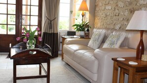 Un salon avec un canapé beige, une table basse en bois, une lampe et un vase rempli de fleurs.