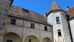 Un bâtiment historique en pierre, doté de fenêtres en arc de cercle et d’une tour.
