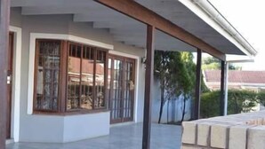 Un porche cubierto con suelo de baldosas, amplias ventanas de madera y vistas a una zona residencial.