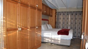 Un dormitorio con cama, armario de madera y cortinas.