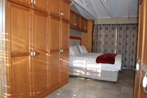 Un dormitorio con cama, armario de madera y cortinas.