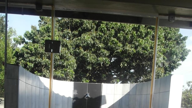 Un vestuario moderno y cerrado con ducha, suelo y paredes alicatadas, con una puerta central y un panel de control en la pared.