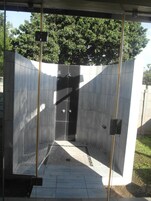 Un vestuario moderno y cerrado con ducha, suelo y paredes alicatadas, con una puerta central y un panel de control en la pared.
