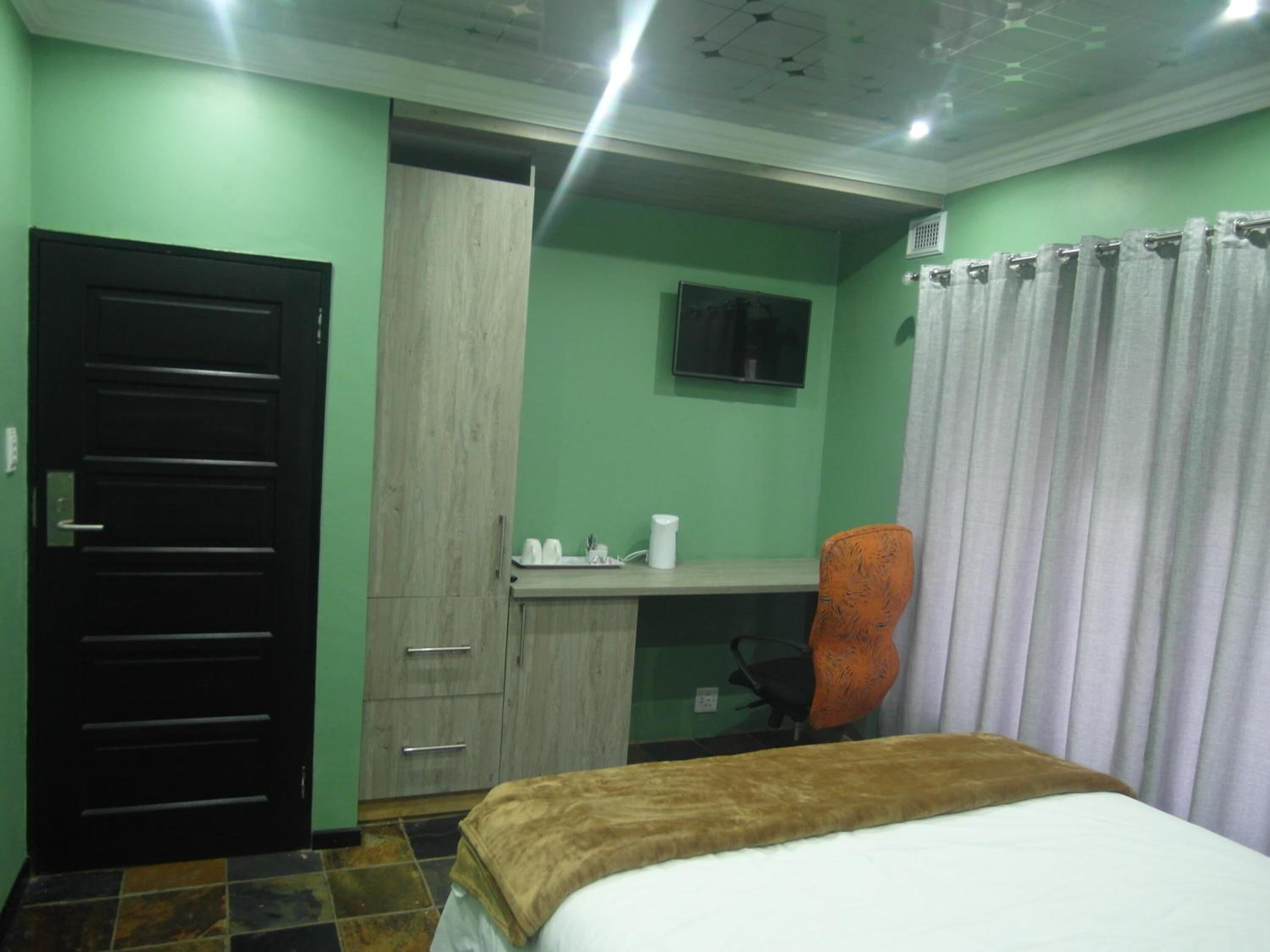 Une chambre d’hôtel comprenant un lit, un bureau, une chaise, une armoire et une salle de bain.