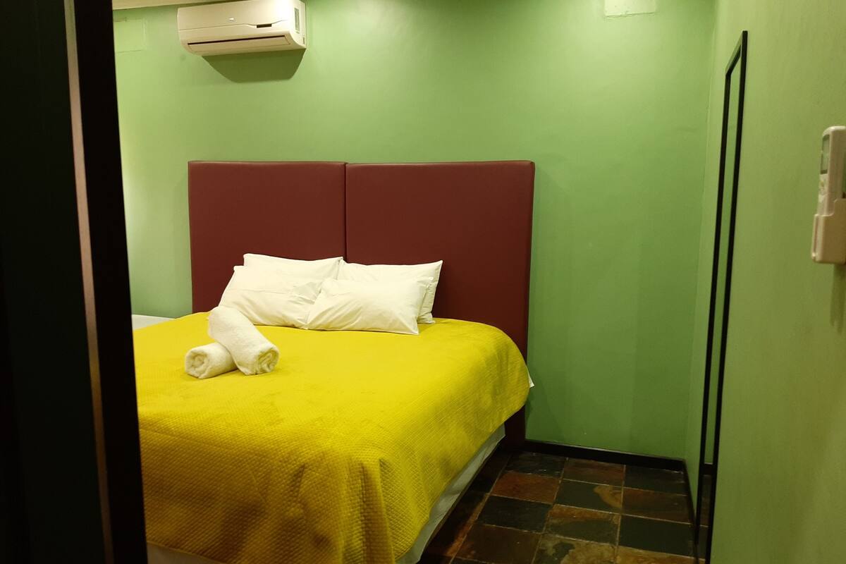 Een hotelkamer met een bed, een rode hoofdbord en een groene muur.