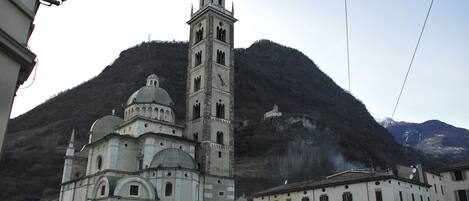 A historic church with a bell tower and a dome, surrounded by a mountainous landscape.