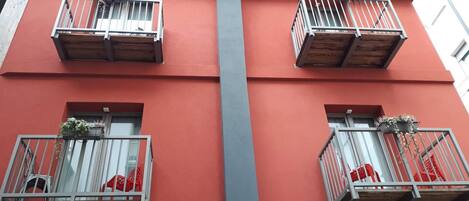 A building with red walls and balconies with metal railings and wooden platforms.